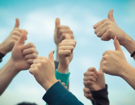 People holding their thumbs up in the air.